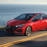 Red 2025 Nissan Versa driving on a coastal highway