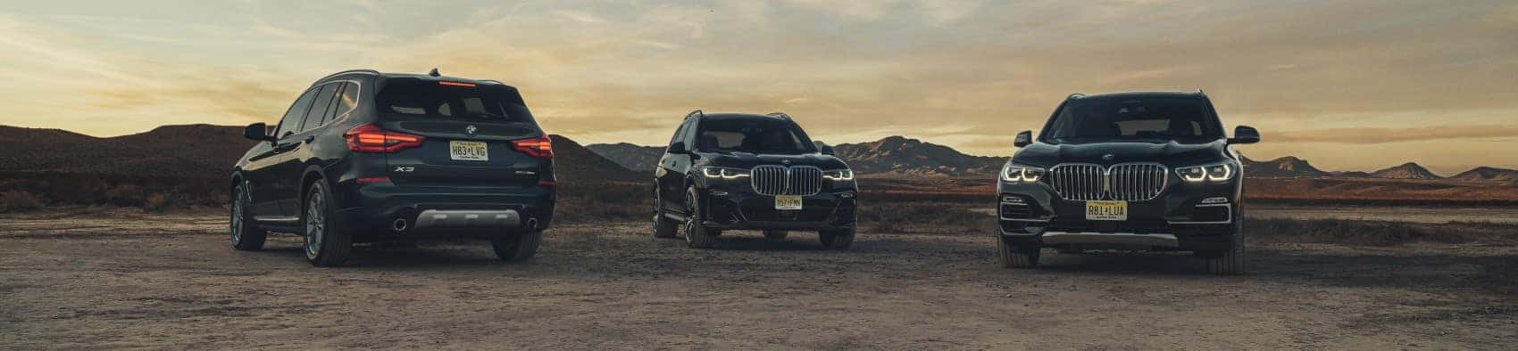 BMW X-Pack Lineup X3 X5 X7 parked in dirt lot horizon in background