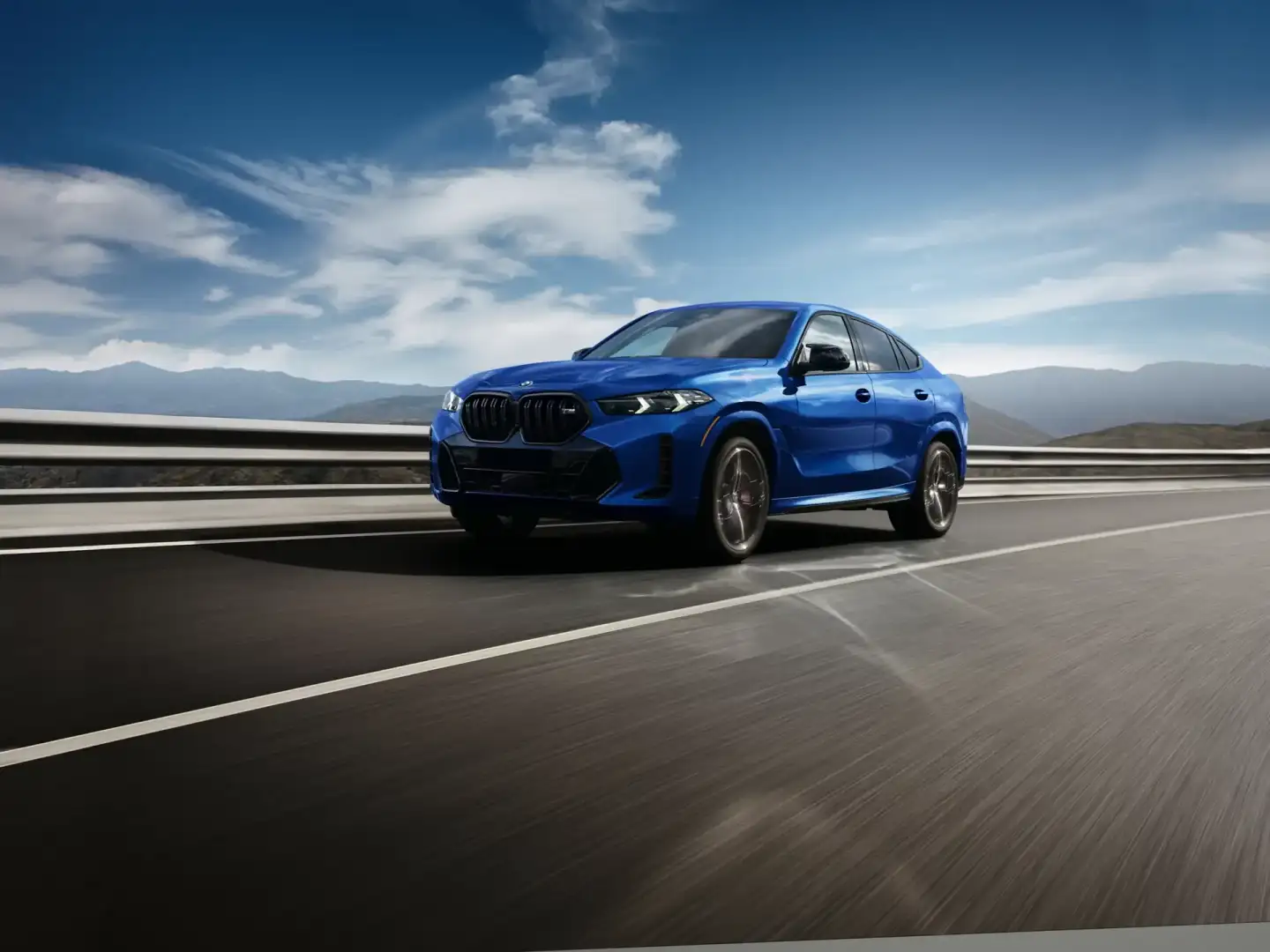 A blue BMW X6 on an open mountain highway, the new 2027 Sports Activity Coupe