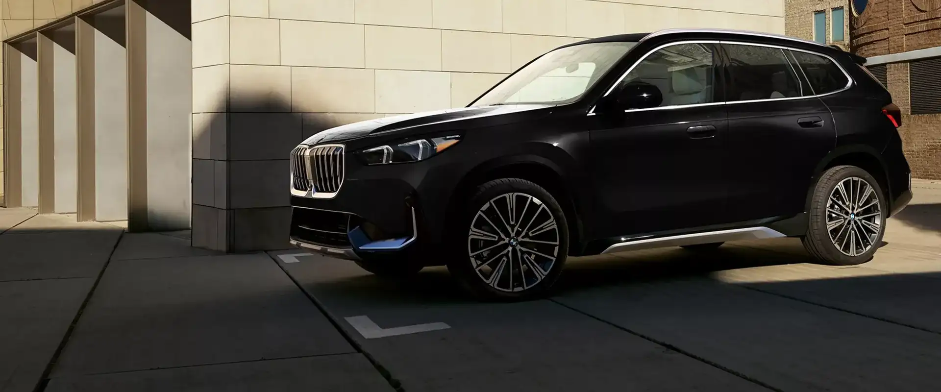 2027 BMW X1 compact luxury SUV in dark metallic paint, shown from the front three-quarter angle