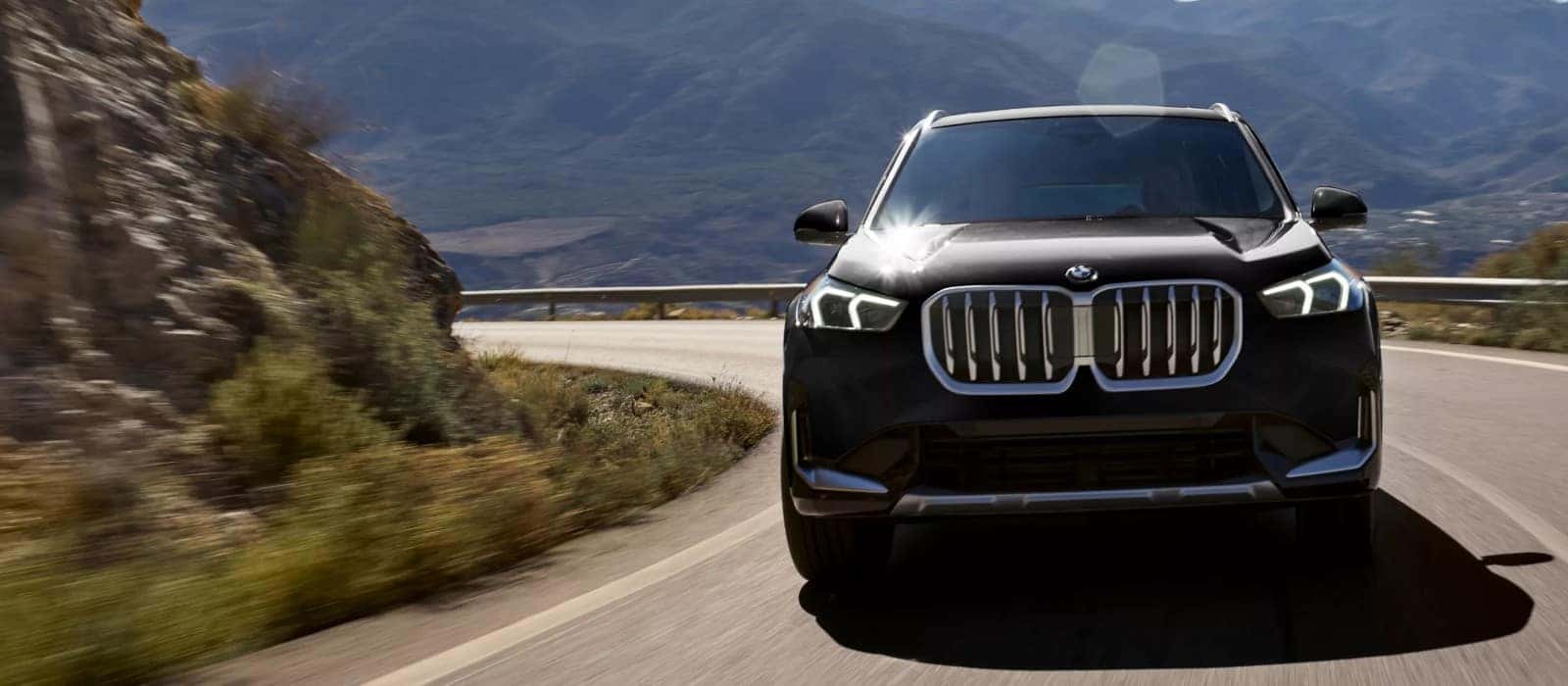 A BMW X1 driving towards the camera on a mountain road