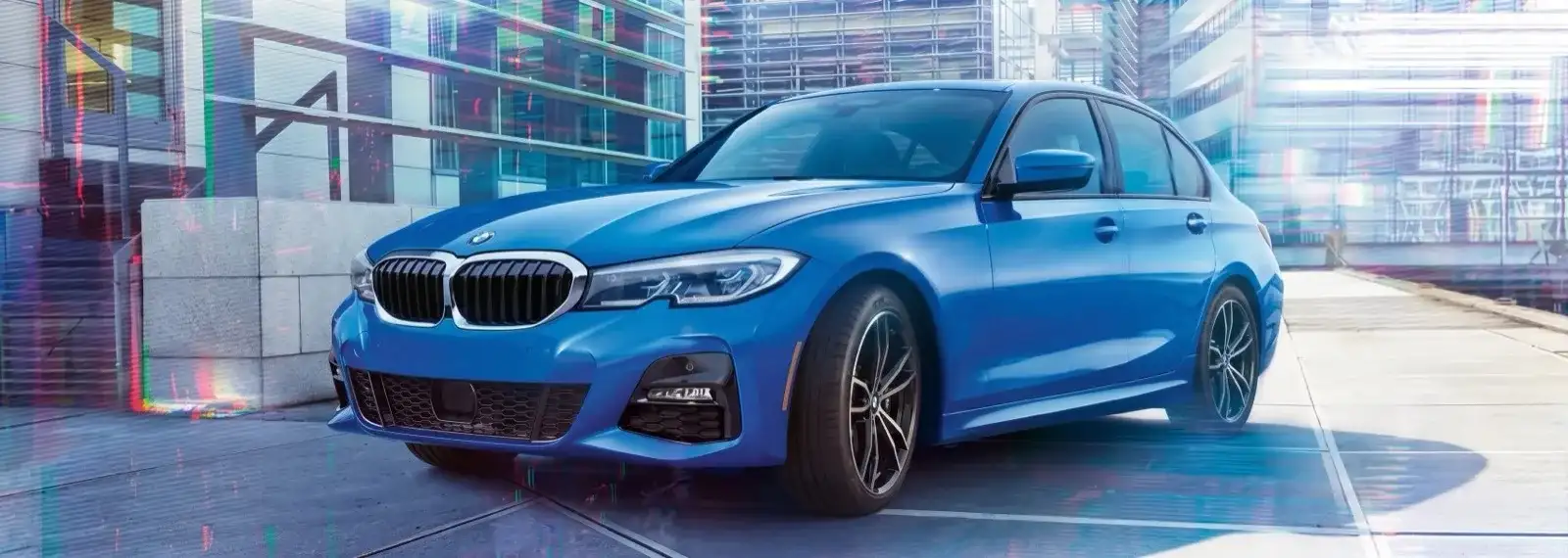 A blue BMW 3 Series M Sport sedan parked in a city plaza