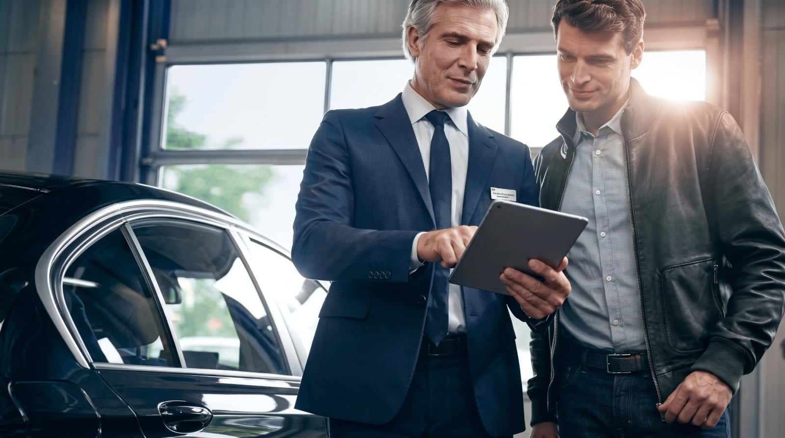 A BMW service advisor walking a customer through the work on a tablet in the service drive