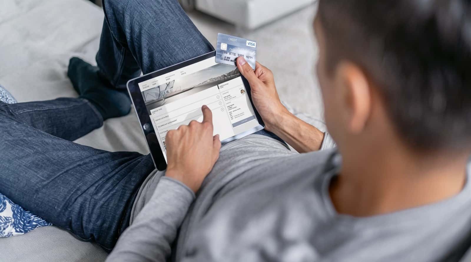 A BMW owner at home with a tablet and a payment card in hand
