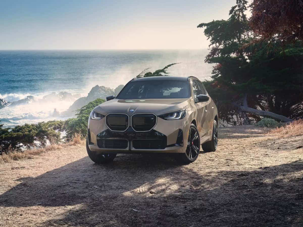 Beige BMW iX electric luxury SUV parked on a scenic coastal overlook, available for a test drive at BMW of Fort Walton Beach.