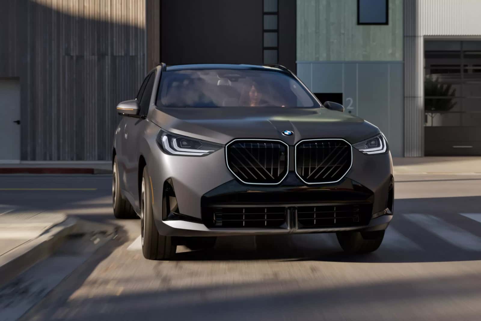 A gray BMW X3 driving through town, seen from the front
