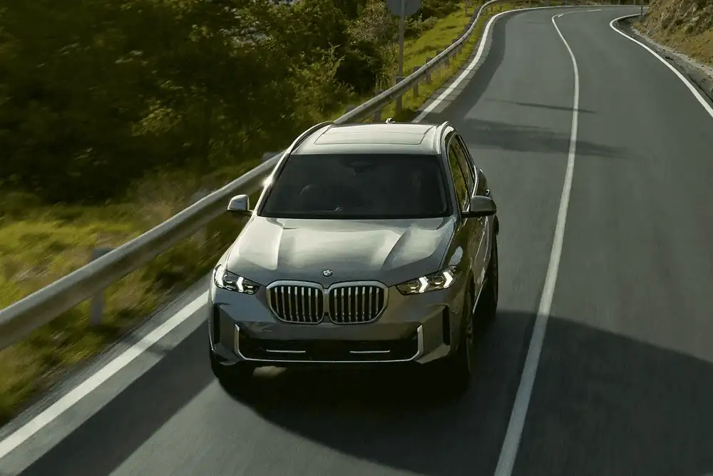 A BMW X5 driving down a winding hill road, seen from above