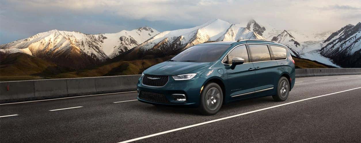 Chrysler minivan driving on a road near a mountain