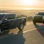 GMC Sierra Trucks driving on a road at sunset