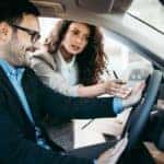 A saleswoman is showing a man the interior of a used car in Milford, CT.