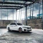 A white 2020 BMW 5 Series is shown parked in an empty warehouse.