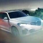 A white 2020 BMW X5 is driving to look at used cars for sale.