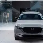 2026 Mazda CX-30 white SUV front view parked outside a modern glass home with black grille