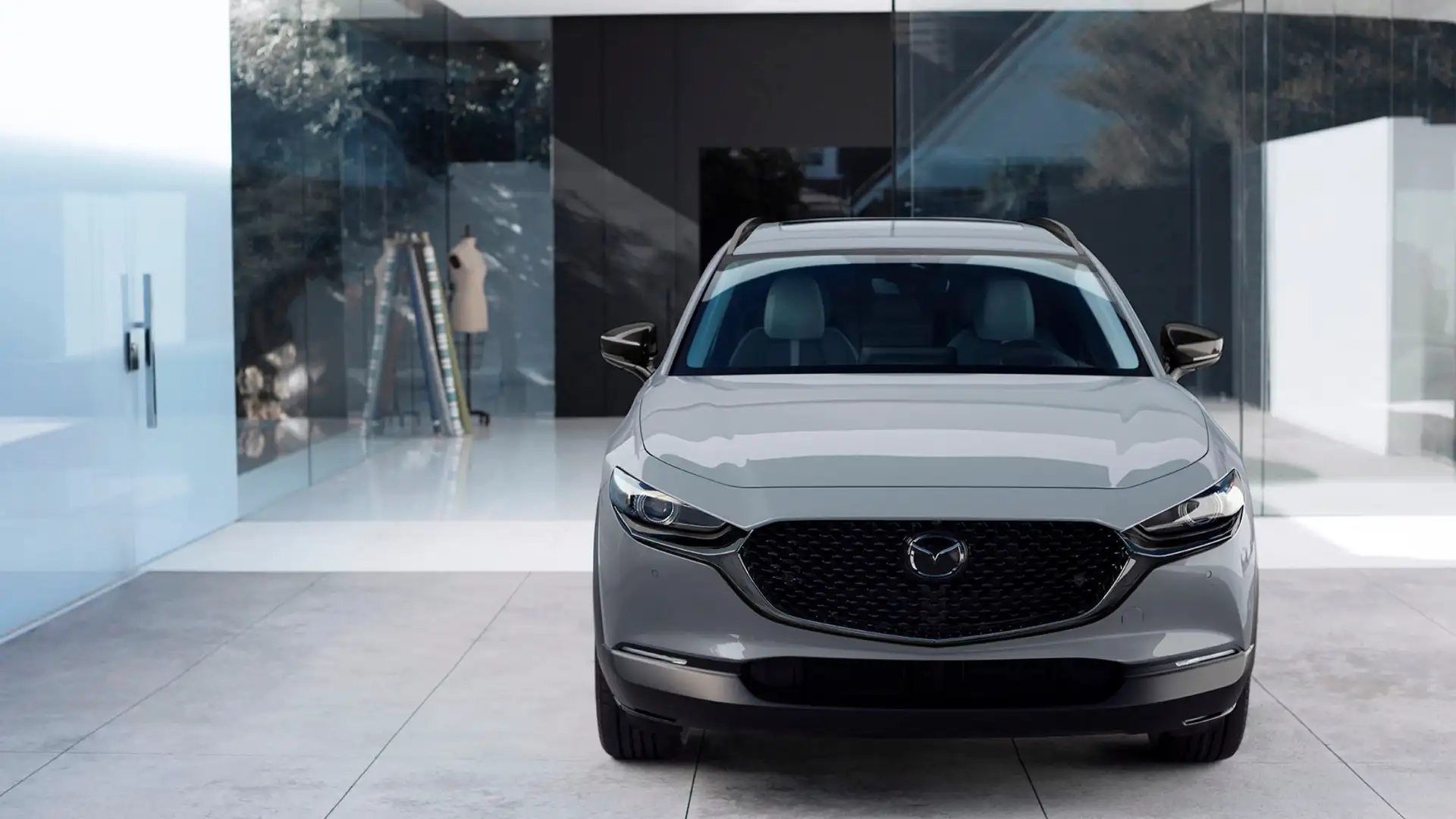 2026 Mazda CX-30 white SUV front view parked outside a modern glass home with black grille
