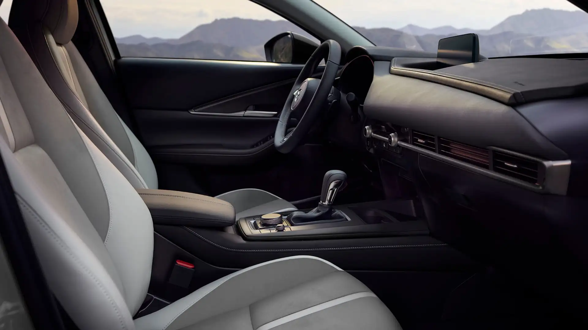 2026 Mazda CX-30 front cabin with two-tone seats, slim dashboard, gear shifter, and mountain view