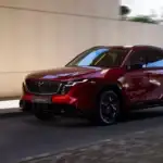2026 Mazda CX-5 red SUV driving through an urban underpass with black wheels and roof rails