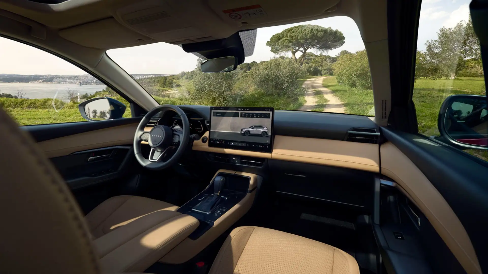 2026 Mazda CX-5 tan dashboard with center touchscreen, driver controls, and scenic dirt road