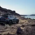 2026 Mazda CX-50 gray SUV parked on rocky canyon terrain overlooking a wide blue lake at dusk
