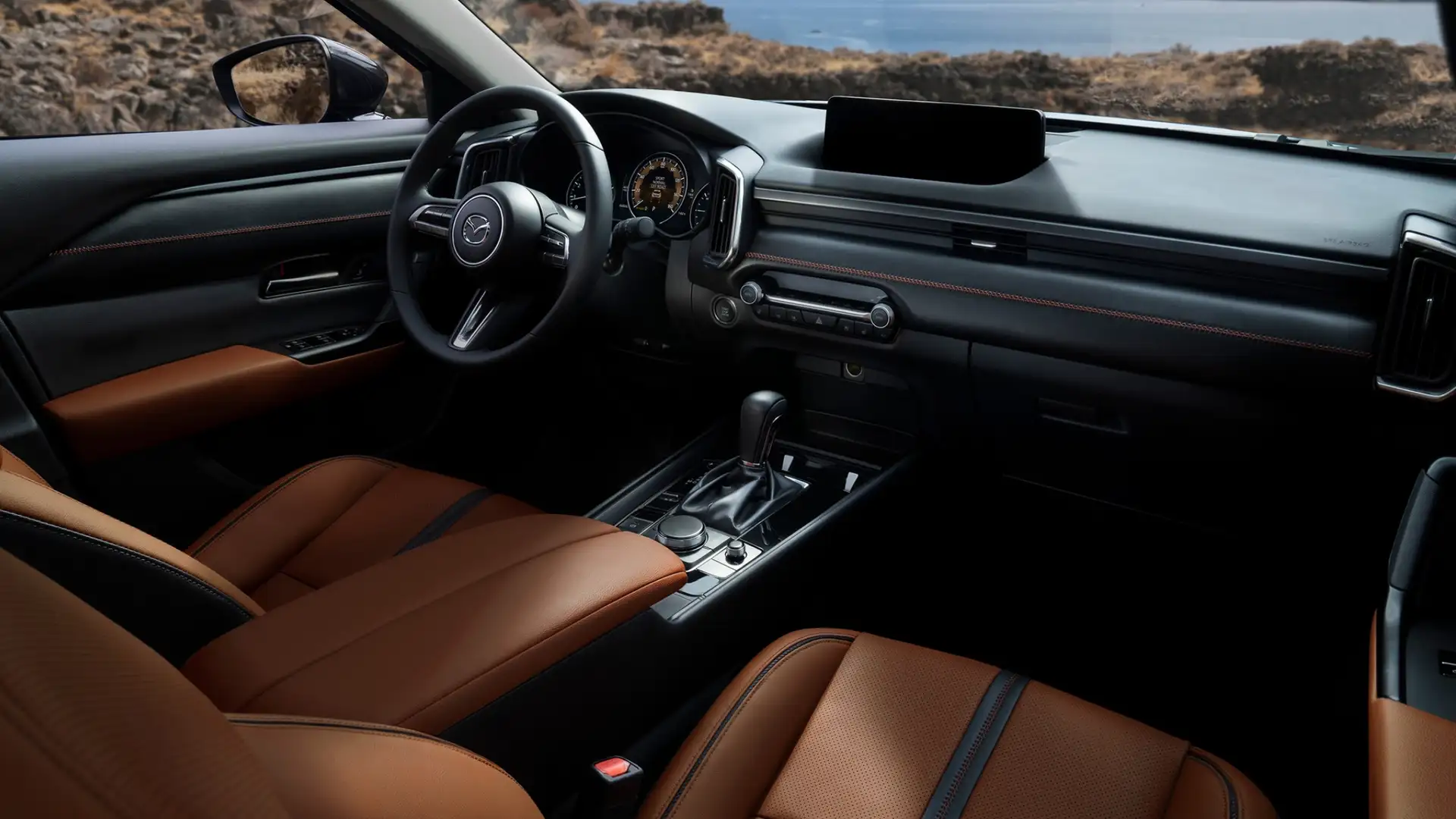 2026 Mazda CX-50 cabin with brown leather seats, wide dashboard, gear shifter, and coastal view