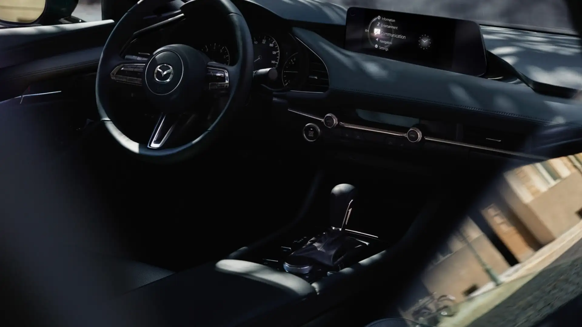 2026 Mazda3 Hatchback dark cockpit with steering wheel, center display, gear selector, and dash