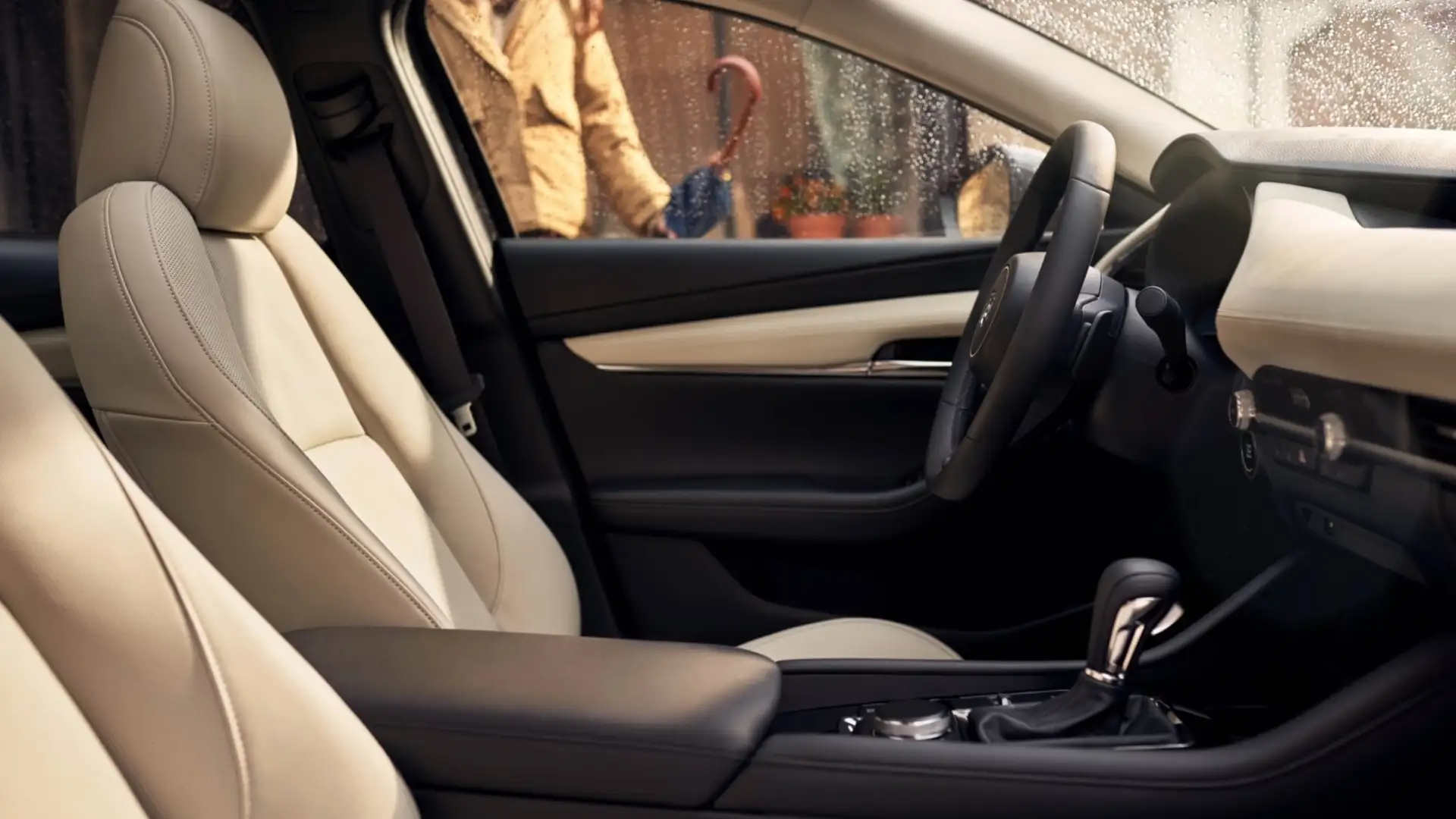 2026 Mazda3 Sedan beige front cabin with rain-speckled window, shifter, and center console
