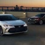 A silver 2020 Toyota Avalon is in front of a burgundy Avalon at sunset.