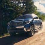 A blue 2021 Toyota Tundra is driving on a dirt road.
