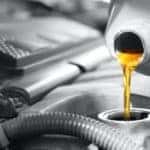 A close up shows oil being poured into an engine.