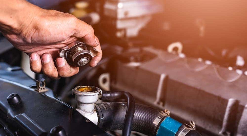 A close up shows a hand removing a radiator cap during a Toyota service near you.