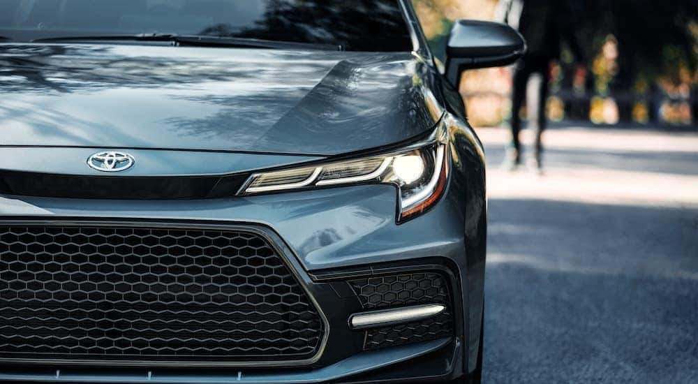 A close up shows the driver side headlight and grille of a pale blue 2021 Toyota Corolla XSE.
