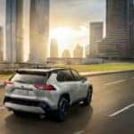 A grey 2021 Toyota RAV4 XSE is shown driving past a city at sunset after leaving a Pennsylvania used Toyota dealer.