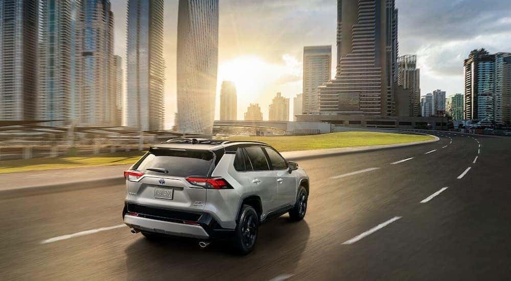 A grey 2021 Toyota RAV4 XSE is shown driving past a city at sunset after leaving a Pennsylvania used Toyota dealer.