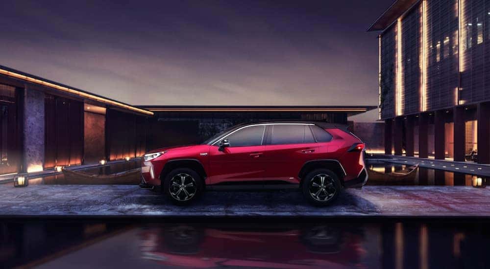 A red 2021 Toyota RAV4 is parked outside of a modern house.