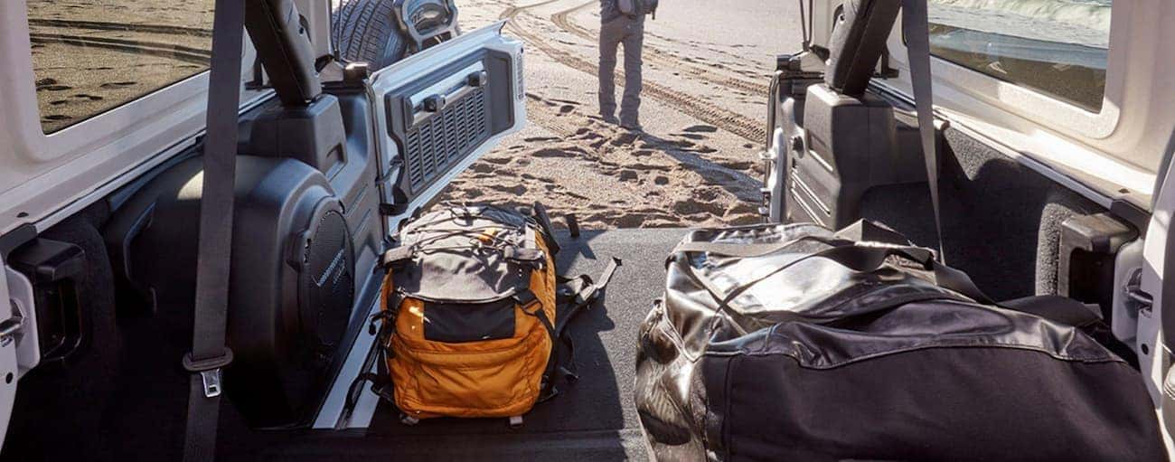 The cargo area is shown in a 2020 Jeep Wrangler with a view of a sandy beach out the back.