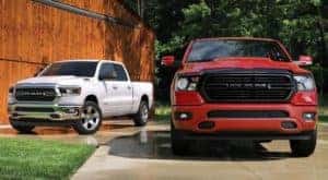 A red and a white 2020 Ram 1500s in front of a barn, find them at Ram Dealership Near Me in Findlay, OH.