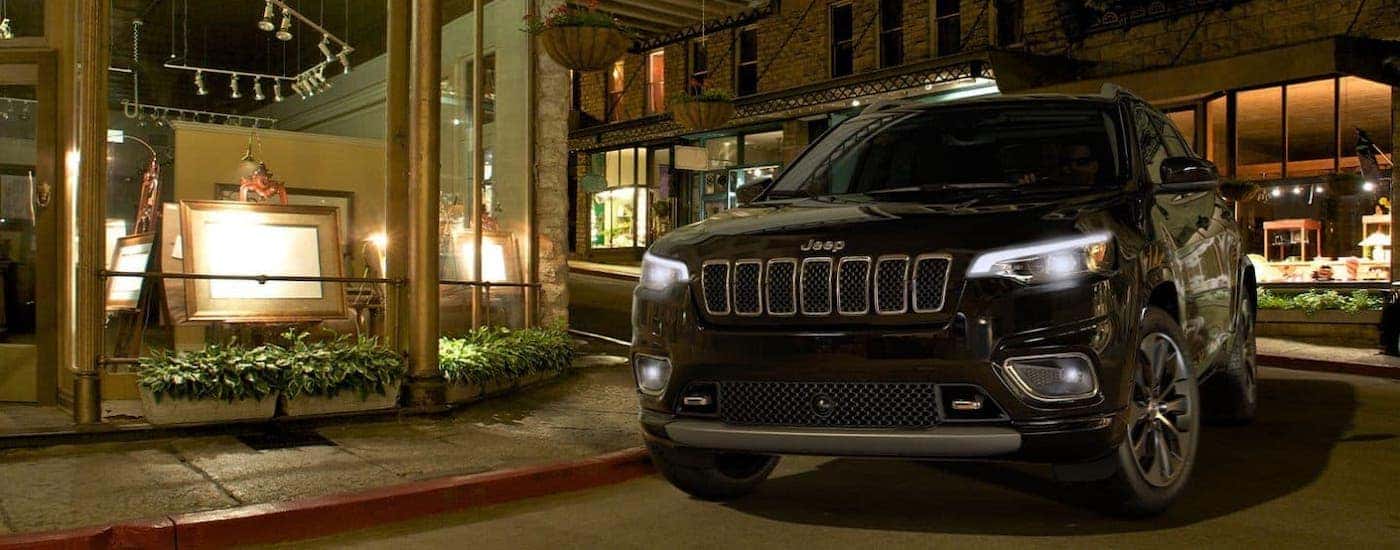 A black 2020 Jeep Cherokee is parked in front of an art gallery in Findlay, OH, at night.