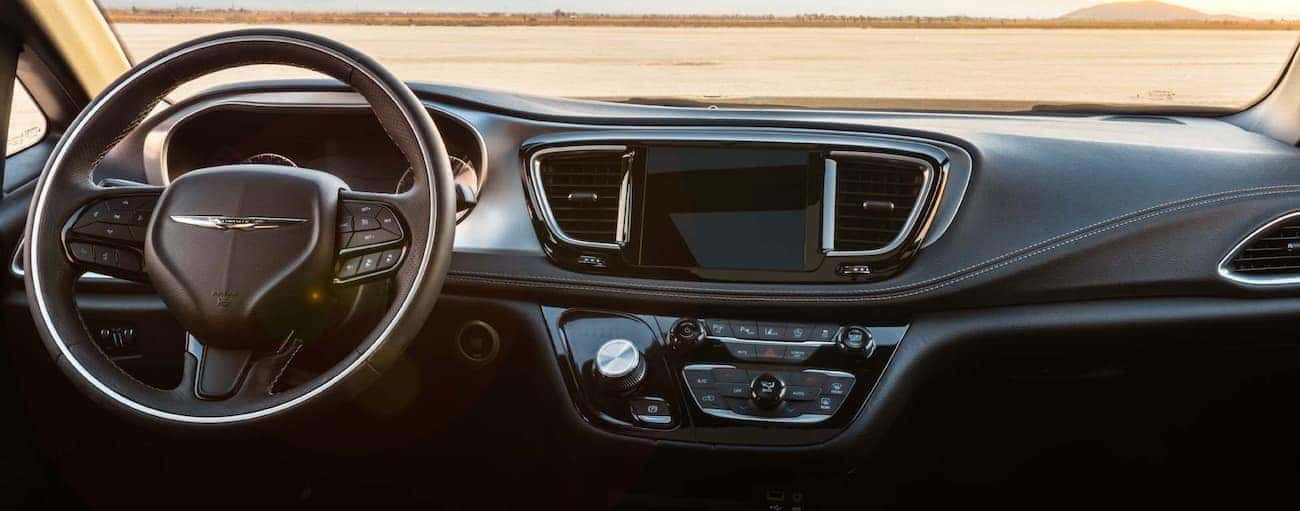 The black dashboard of a 2020 Chrysler Pacifica is shown with distant mountains in the windshield.
