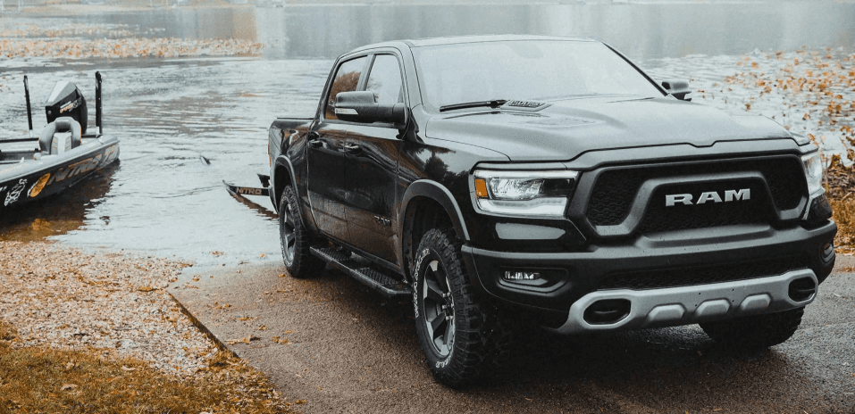 Ram pickup truck launching boat at lakeside ramp