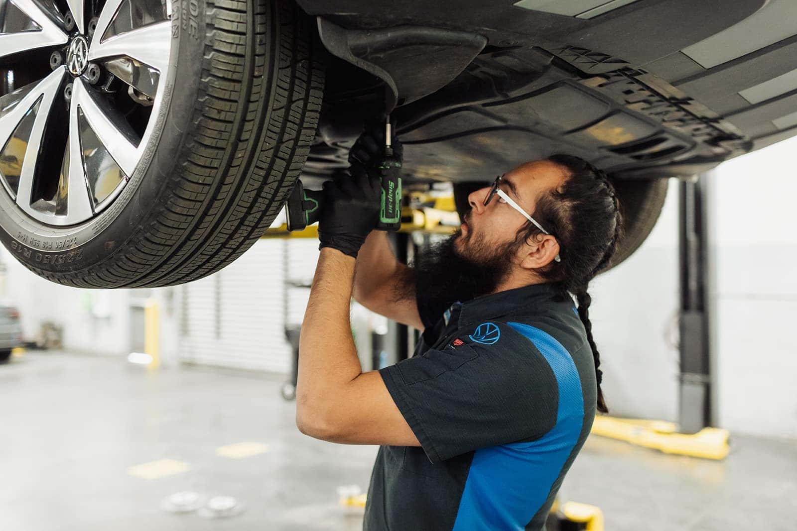 Employee working underneath Car that is on a Lift