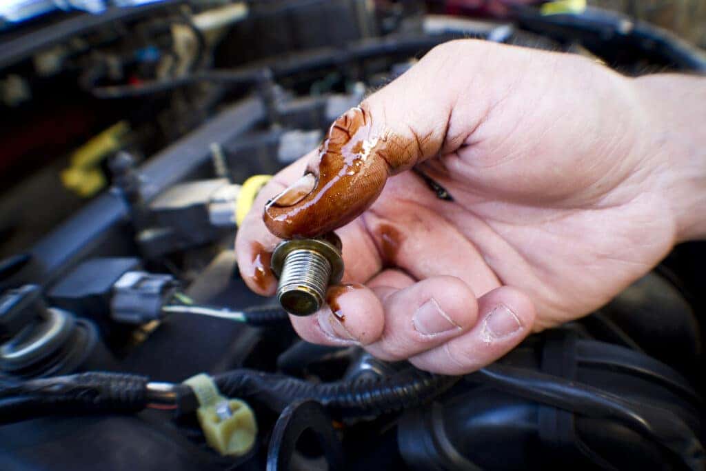 Mechanic works on a car and holds a dirty bolt. Dirty hands.