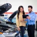 Hyundai service technician consulting with a customer while a car's hood is open