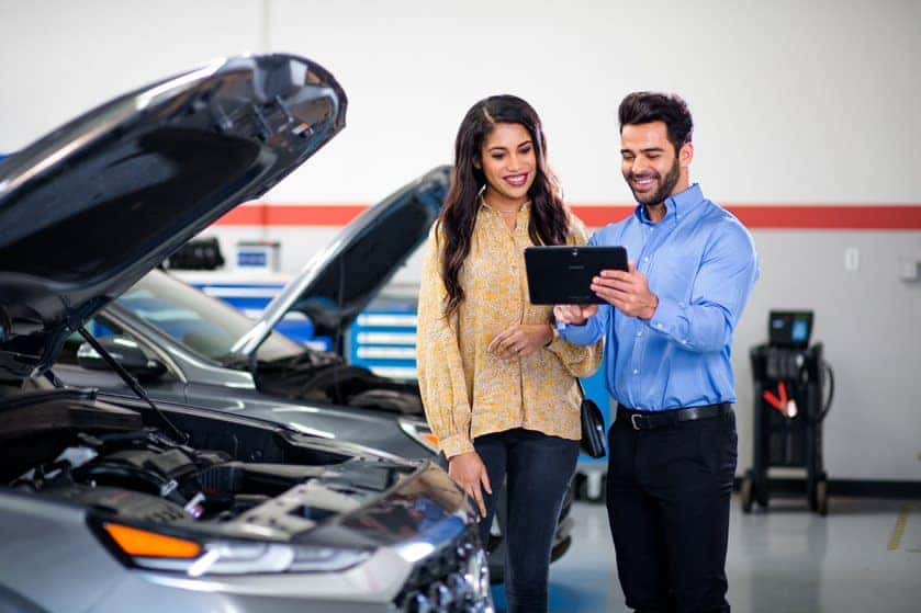 Hyundai service technician consulting with a customer while a car's hood is open