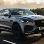 Gray Jaguar F-Pace driving on a scenic road with trees in the background