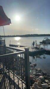Shane Martin standing on the dock of Prior Lake holding his guitar and singing into a microphone