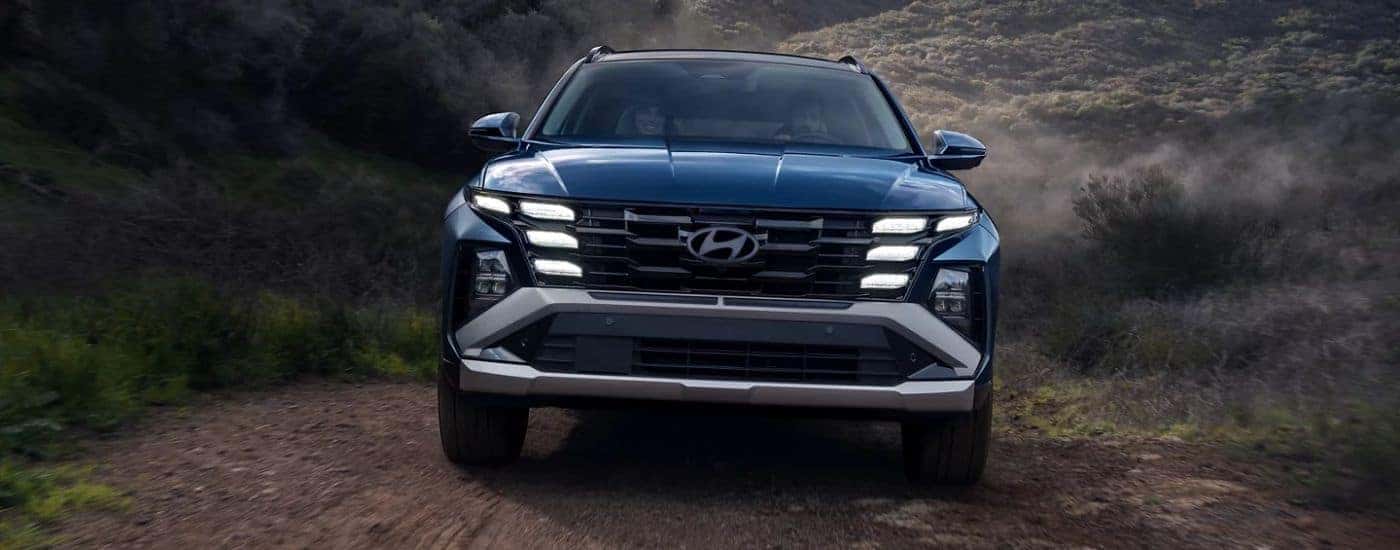 A blue 2026 Hyundai Tuscon Limited shown driving a trail head-on.