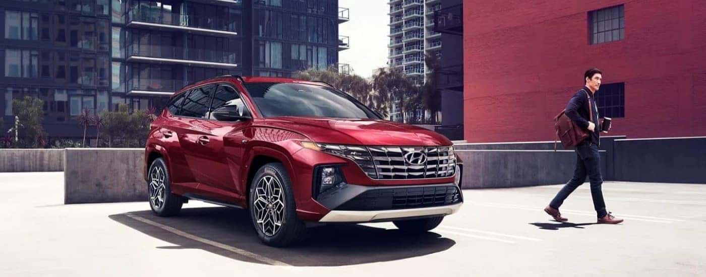 A red 2023 Hyundai Tucson N-Line parked with a person walking away.