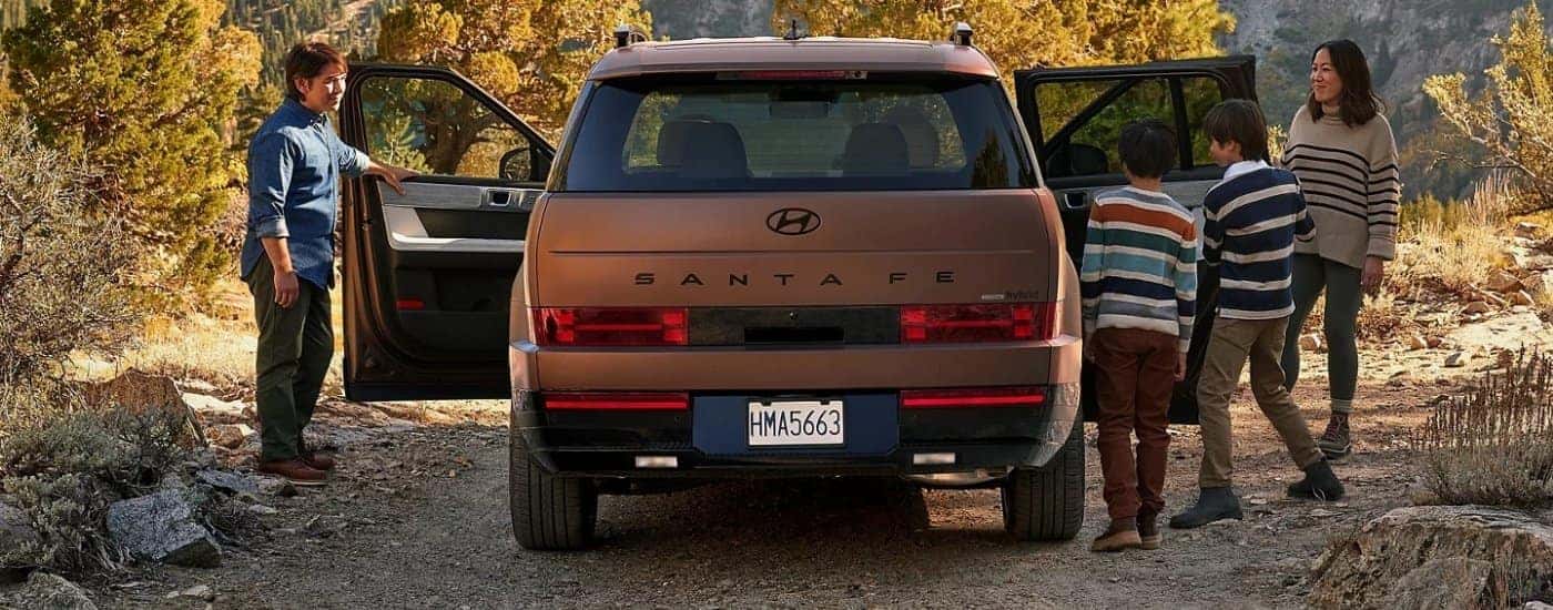 Rear view of a brown 2025 Hyundai Santa Fe with people getting side