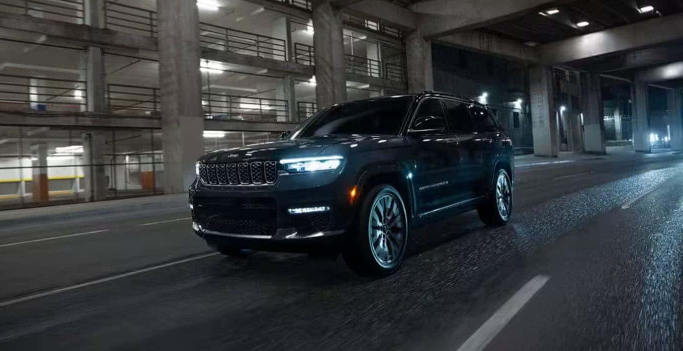 Black Jeep Grand Cherokee driving through a dimly lit urban tunnel at night.