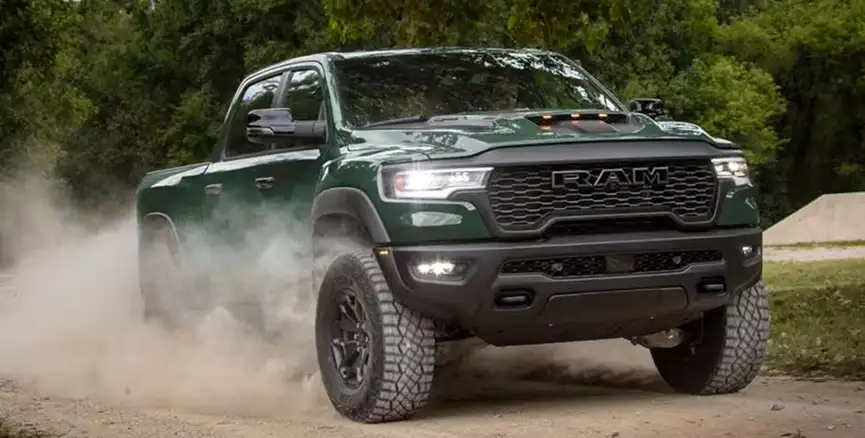 Dark green RAM 1500 kicking up dust while climbing a gravel trail