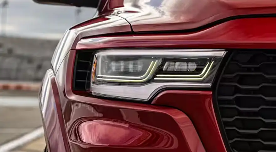Close-up of the illuminated LED headlamp and grille on a red RAM 1500